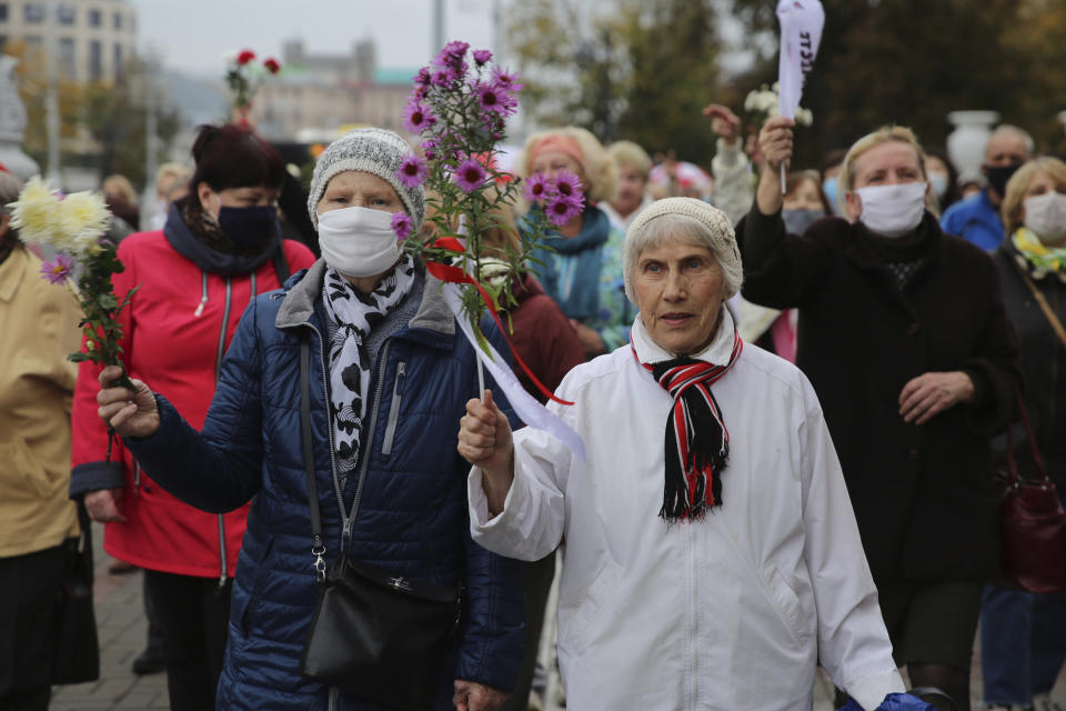 Elderly women hold flowers during an opposition rally to protest the official presidential election results in Minsk, Belarus, Monday, Oct. 12, 2020. Riot police clashed with protesting pensioners in central Minsk on Monday. The pensioners marched in a column through central Minsk, carrying flowers and posters with slogans such as "The grandmas are with you (protesters)." (AP Photo)