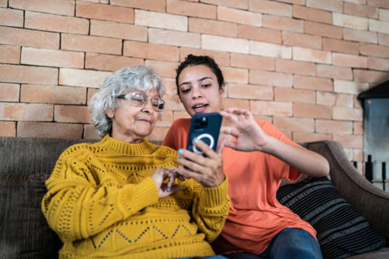 Granddaughter helping grandmother to use the mobile phone at home