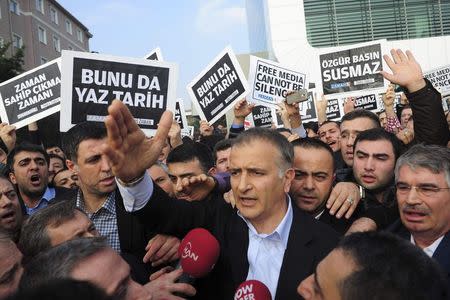 Zaman editor-in-chief Ekrem Dumanli, surrounded by his colleagues and plainclothes police officers (C), reacts as he leaves the headquarters of Zaman daily newspaper in Istanbul December 14, 2014. REUTERS/Yagiz Karahan