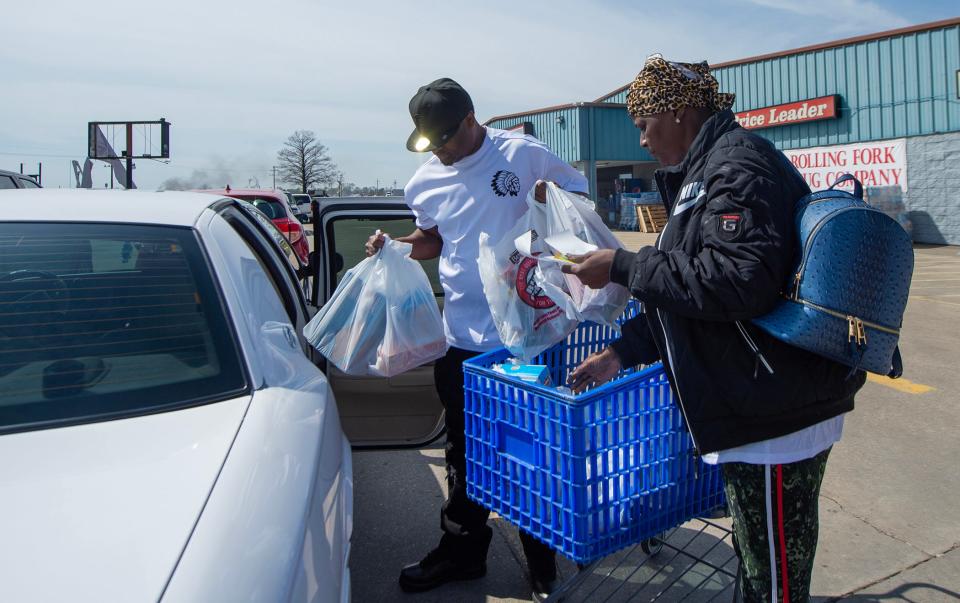 Sonia Qualls, right, and Michael Vogel, center, both of Rolling Fork, load groceries for family members who are still living in Rolling Fork on Tuesday. The couple is staying in Vicksburg, 45 miles away. The grocery store, Stop-N-Shop, is open and running business on a generator after a tornado ripped through the small Delta town last Friday.