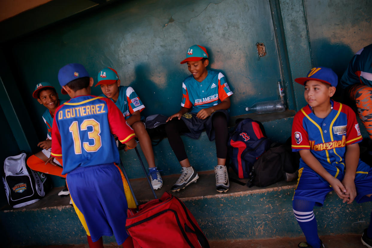 Baseball little league players Adrian Salcedo, 13 (L), Ibrahim Ruiz, 13 (2nd L) and Eduar Pinto, 12 (C), talk with teammates prior to training at Cacique Mara stadium in Maracaibo, Venezuela. (Photo: Manaure Quintero/Reuters)