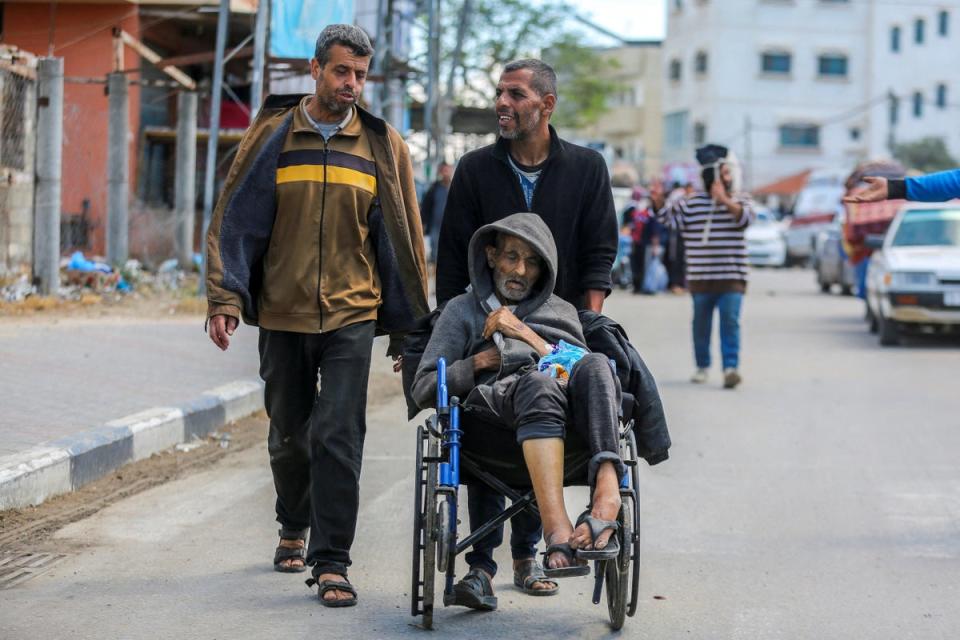 An elderly man is pushed in a wheelchair as Palestinians leave Rafah ahead of a long-anticipated Israeli invasion of the area (Reuters)