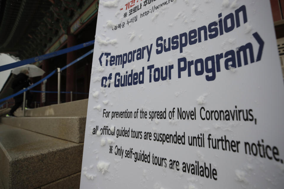 A visitor wearing a face mask walks near the banner showing the temporary suspension of the guided tour program due to the coronavirus at the Gyeongbok Palace, one of South Korea's well-known landmarks, in Seoul, South Korea, Sunday, Dec. 13, 2020. (AP Photo/Lee Jin-man)