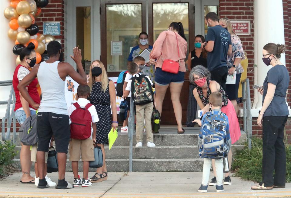 Staff members at Port Orange Elementary School greet students and check their temperatures at the front door on Aug. 31, the first day of school in Volusia County in Florida.