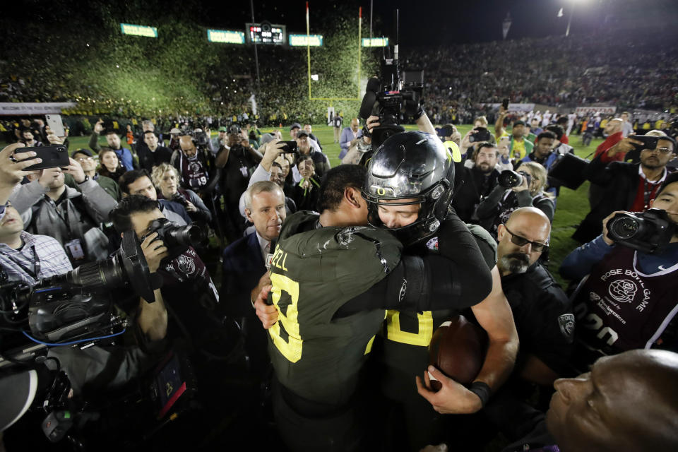 Oregon quarterback Justin Herbert, right, hugs offensive lineman Penei Sewell after their win against Wisconsin in the Rose Bowl NCAA college football game Wednesday, Jan. 1, 2020, in Pasadena, Calif. (AP Photo/Marcio Jose Sanchez)