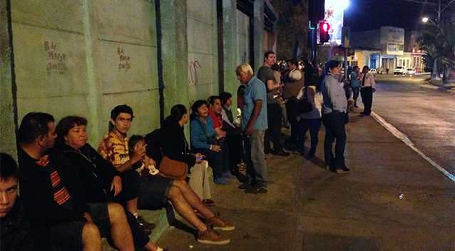 Locals sit on the street following a tsunami alert after a powerful 8.0-magnitude earthquake hit off Chile's Pacific coast. Photo: AAP.