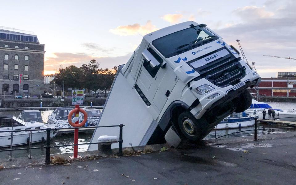 Three fire engines, one heavy rescue tender, a boat and firefighters are using winches to stop the HGV from sinking. - SWNS