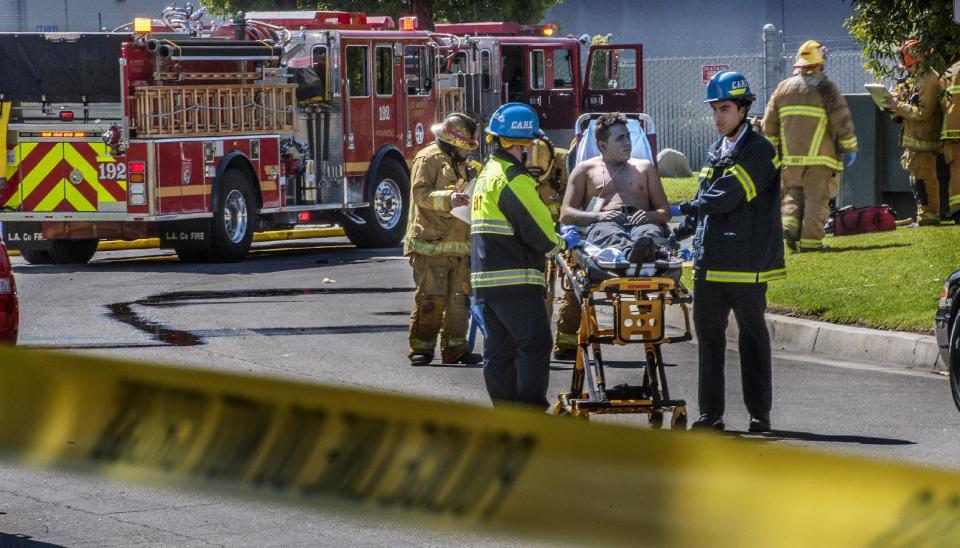 An injured worker is moved toward a waiting ambulance after an explosion was reported at a business in La Habra, Calif., Tuesday, April 29, 2014. Authorities say eight people have been hurt, three critically, in an explosion and fire at a commercial building in south Los Angeles County. (AP Photo/The Orange County Register, Bruce Chambers)