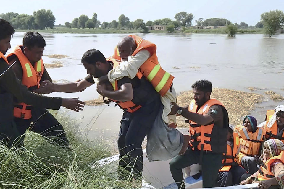 In this photo released by Rescue 1122 Emergency Department, rescue workers help a villager after he with others being evacuate from a flooded area of Bahawalnagar district in Pakistan's Punjab province, Wednesday, Aug. 23, 2023. Rescuers have evacuated more than 100,000 people from flood-hit areas of Pakistan's eastern Punjab province in the past three weeks, officials said Wednesday. (Rescue 1122 Emergency Department vis AP)