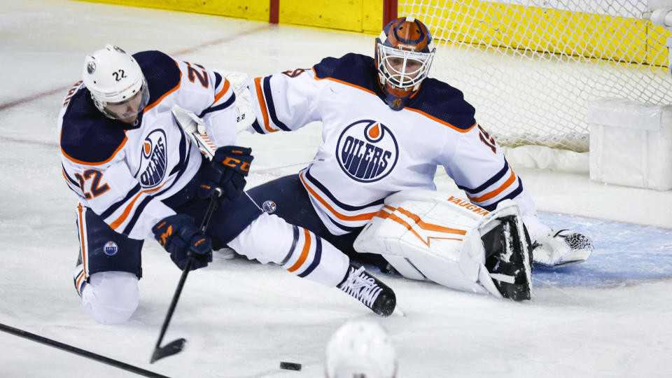 Edmonton Oilers defenseman Tyson Barrie, left, clears the puck away from in front of Oilers goalie Mikko Koskinen during the second period of Game 1 of an NHL hockey second-round playoff series against the Calgary Flames on Wednesday, May 18, 2022, in Calgary, Alberta. (Jeff McIntosh/The Canadian Press via AP)