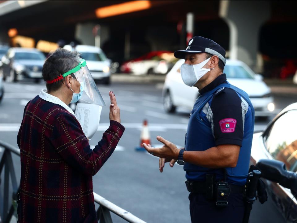 A local police officer speaks with a woman during the first day of partial lockdown in Madrid (REUTERS)