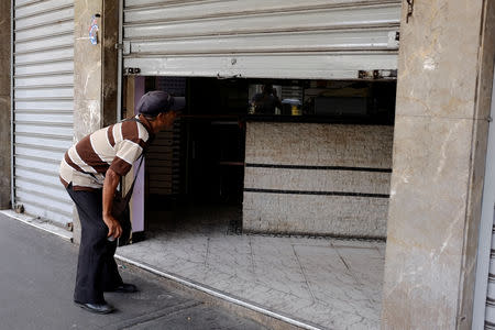A man looks inside a store, through a security gate partially closed, in Caracas, Venezuela September 14, 2018. REUTERS/Marco Bello
