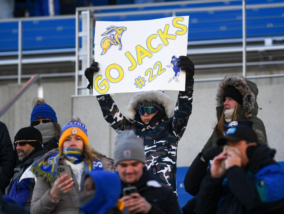 A young South Dakota State football fan bundles up for the cold while holding a sign for running back Isaiah Davis in an FCS playoff game against Delaware on December 3, 2022, at Dana J. Dykhouse Stadium in Brookings.