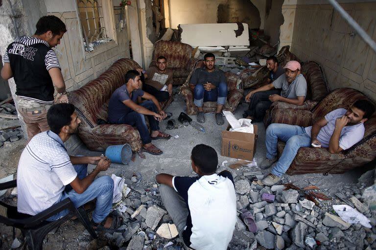 Un grupo de hombres palestinos sentados en lo que quedó de un living en una casa en Shejaiya, Gaza