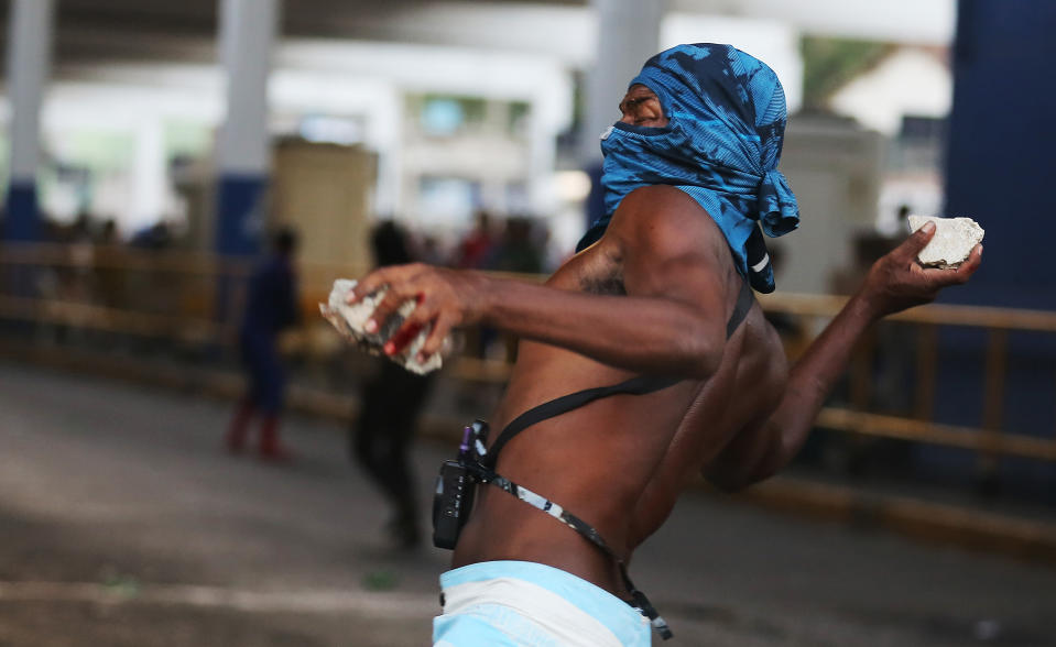 A demonstrator throws rocks at police outside the central train station, during protest against the increase on bus fares in Rio de Janeiro, Brazil, Thursday, Feb. 6, 2014. Last year, millions of people took to the streets across Brazil complaining of higher bus fares, poor public services and corruption while the country spent billions on the World Cup, which is scheduled to start in June. (AP Photo/Leo Correa)