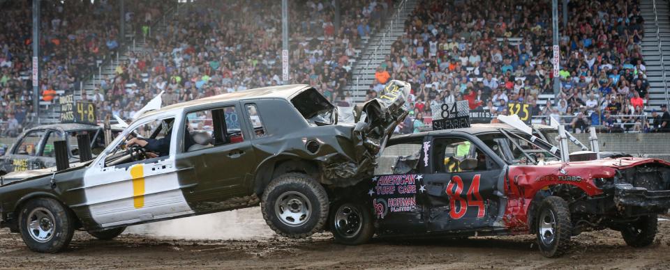 Mark Pardeike, of Monroe in car #1, drives up onto the car driven by Zack Salenbien, of Dundee,  Tuesday evening in the Demolition Derby at the Monroe County Fair.