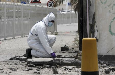 An explosives specialist police officer conducts an investigation after a bomb blast in the village of Sitra, south of Manama, Bahrain, July 28, 2015. REUTERS/Hamad I Mohammed