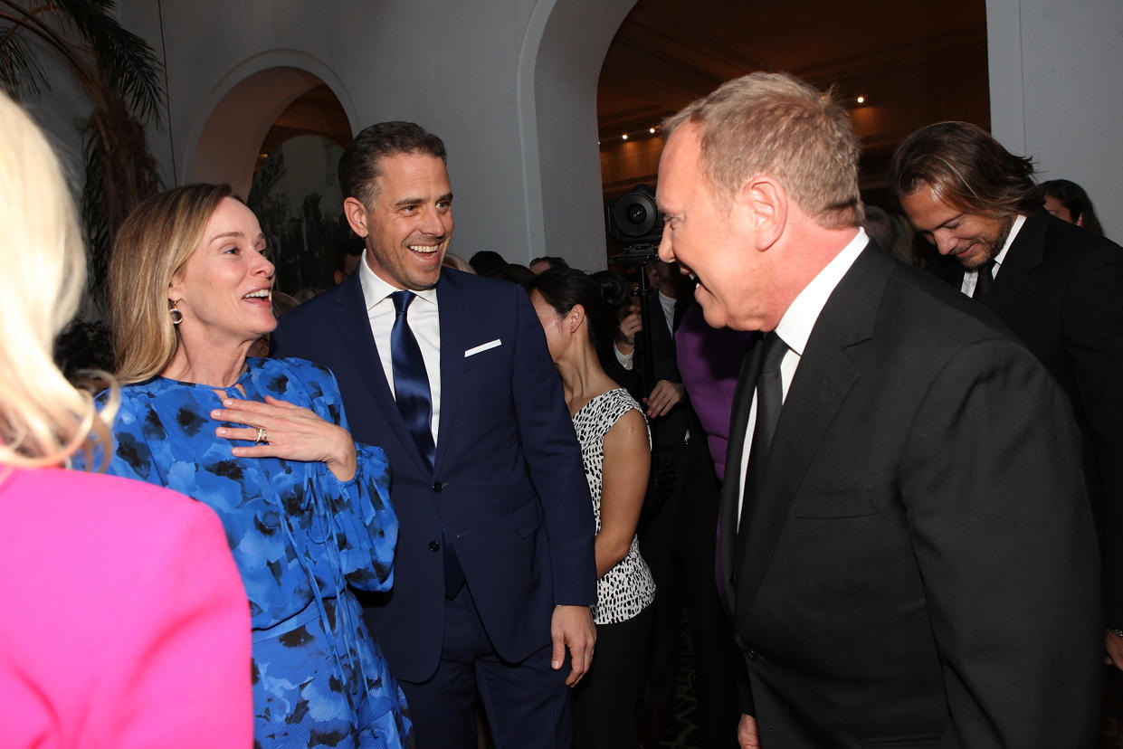 Kathleen Biden, Hunter Biden and designer Michael Kors smile while speaking to each other in a room with others
