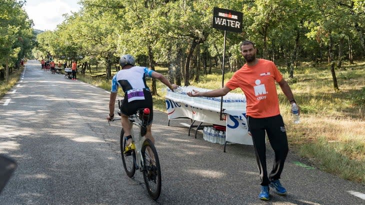 A triathlete takes water from an aid station as part of a 70.3 nutrition plan.