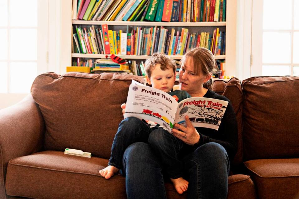 Emerson Jones, 3, and his mom, Erin Rinn, read a book at the family’s Raleigh home on Wednesday, Jan. 26, 2022. Jones’ daycare class has been closed since Jan. 4th due to a COVID exposure. Despite multiple negative tests, including seven PCR tests, Jones’ can’t rejoin his class until Feb. 3, 2022, so his parents are both balancing his care with working from home.