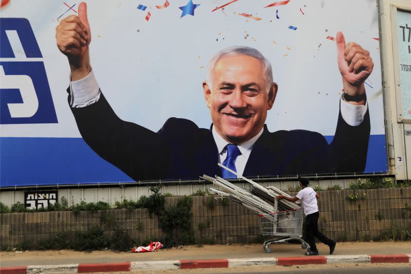 A man walks past a Likud party election campaign banner depicting its leader, Israeli Prime Minister Benjamin Netanyahu, ahead of the March 23 ballot, in Bnei Brak