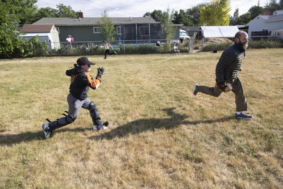 Brady Hill, 14, runs to third base trying to outrun the tag of his father Nathan after a hit by his sister Meisha at their home in Meridian, Idaho, June 19, 2023. Brady survived a rare brain cancer as a baby, but requires round the clock care. Families of severely disabled children across the country are worried about the future of crucial Medicaid payments they started receiving to provide care during the COVID-19 pandemic. (AP Photo/Kyle Green)