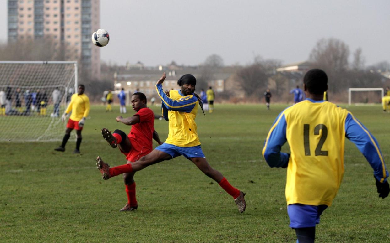 Two Sunday League footballers challenge for the ball during a match on the Hackney Marshes' pitches  - GETTY IMAGES