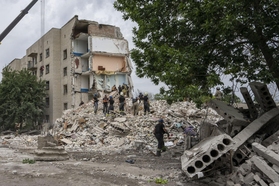 Rescue workers stand on the rubble at the scene in the after math of a missile strike that his a residential apartment block, in Chasiv Yar, Donetsk region, eastern Ukraine, Sunday, July 10, 2022. (AP Photo/Nariman El-Mofty)