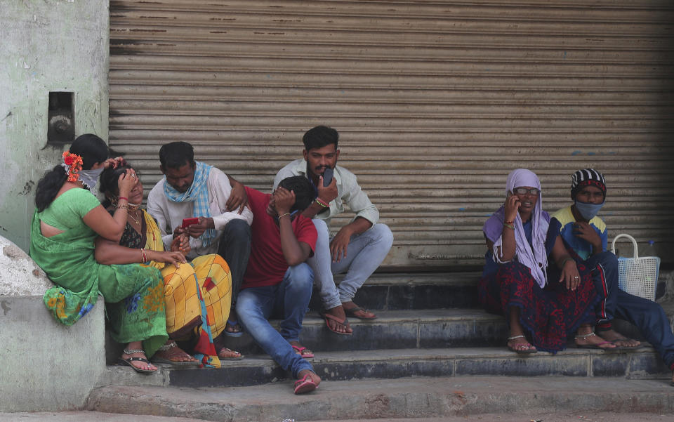 Daily wage laborers wait to be employed, in front of a closed shop in Hyderabad, India, Saturday, July 11, 2020. In just three weeks, India went from the world’s sixth worst-affected country by the coronavirus to the third, according to a tally by Johns Hopkins University. India's fragile health system was bolstered during a stringent monthslong lockdown but could still be overwhelmed by an exponential rise in infections. (AP Photo/Mahesh Kumar A.)