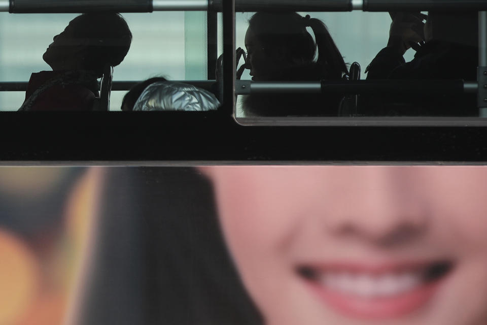 In this Jan. 12, 2019, photo, commuters ride on a bus with a smiling face advertisement at the Central Business District in Beijing. China's slowing economy is squeezing the urban workers and entrepreneurs the ruling Communist Party is counting on to help transform this country from a low-wage factory floor into a prosperous consumer market. (AP Photo/Andy Wong)