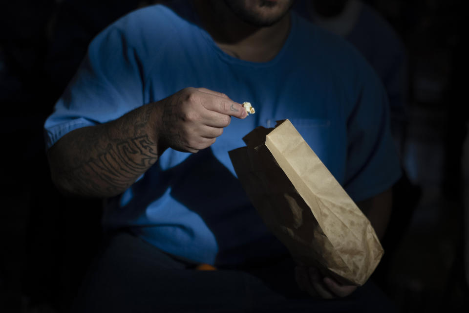 Miguel Rodriguez, a 24-year-old resident at Valley State Prison, eats his popcorn while watching a personal documentary film, "The Death of My Two Fathers," by director Sol Guy in the prison's gymnasium in Chowchilla, Calif., Friday, Nov. 4, 2022. (AP Photo/Jae C. Hong)