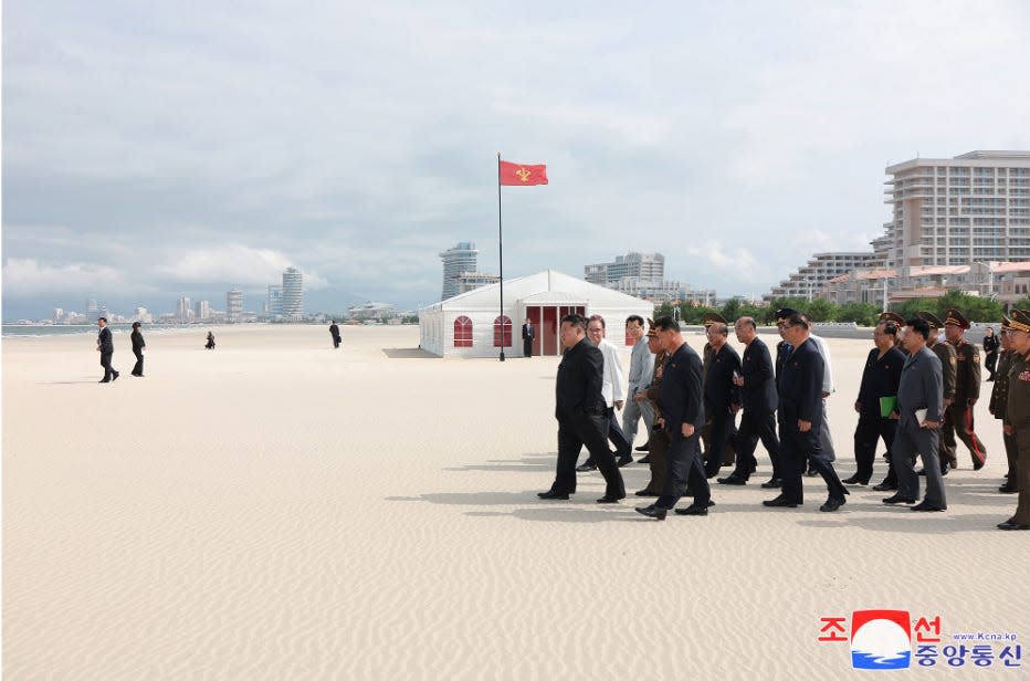 Kim Jong Un walks across beach with deputies.