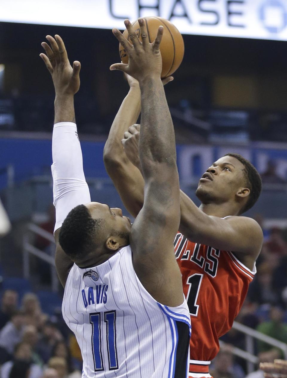 Chicago Bulls' Jimmy Butler, right, takes a shot over Orlando Magic's Glen Davis (11) during the first half of an NBA basketball game in Orlando, Fla., Wednesday, Jan. 15, 2014. (AP Photo/John Raoux)