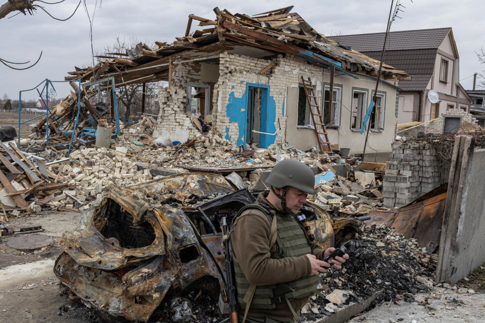 A Ukrainian serviceman checks his mobile phone in front of a destroyed house, as Russia's attack on Ukraine continues, in the village of Krasylivka outside Kyiv, Ukraine March 26, 2022. REUTERS/Marko Djurica