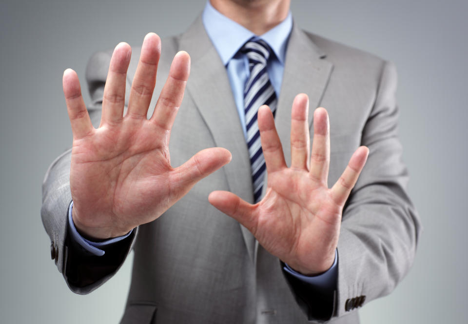 A businessman in a suit putting his hands up as if to say, "No, thanks."