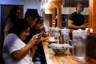 Digell Huang, 34, one of the two reserved customers takes photos of the giant isopod ramen in Taipei