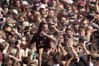 St. Pauli's Jackson Irvine celebrates with fans who invaded the field after their team won 3-1 during a Bundesliga 2 soccer match between St. Pauli and VfL Osnabrück, at the Millerntor Stadium, in Hamburg, Germany, Sunday, May 12, 2024. (Christian Charisius/dpa via AP)