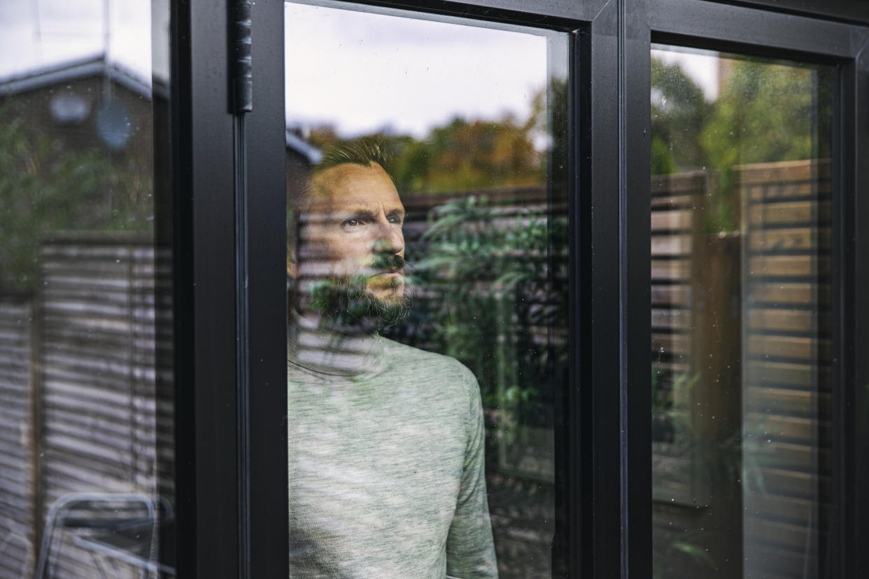 Man looking depressed looking out window. (Getty Images)