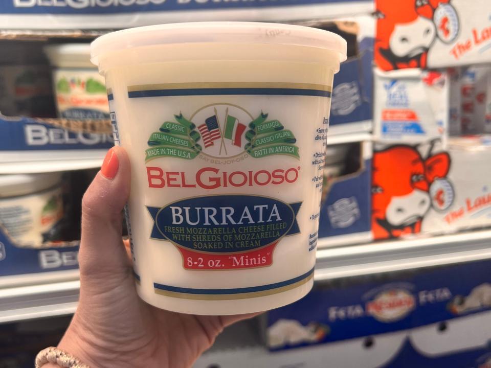 hand holding up a big tub of burrata cheese at costco