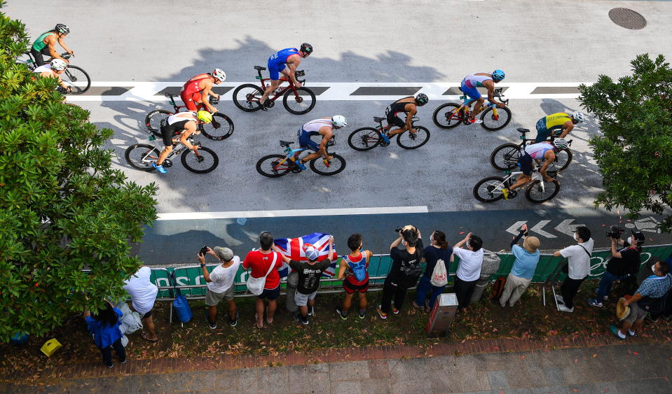 <p>A general view of the peleton as they pass spectators during the cycling discipline of the men's triathlon at the Odaiba Marine Park during the 2020 Tokyo Summer Olympic Games in Tokyo, Japan. (Photo By Ramsey Cardy/Sportsfile via Getty Images)</p> 