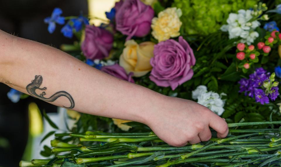 Jade Lehman, a lead intern with the Marion County Coroner's Office, places a carnation on a casket Thursday, June 8, 2023, at Floral Park Cemetery during a burial service for 75 people who died in Marion County but were never claimed from 2020 to 2021.