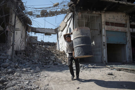 A man carries a barrel as people collect steel from a destroyed building in Mosul, Iraq April 17, 2017. REUTERS/Marko Djurica