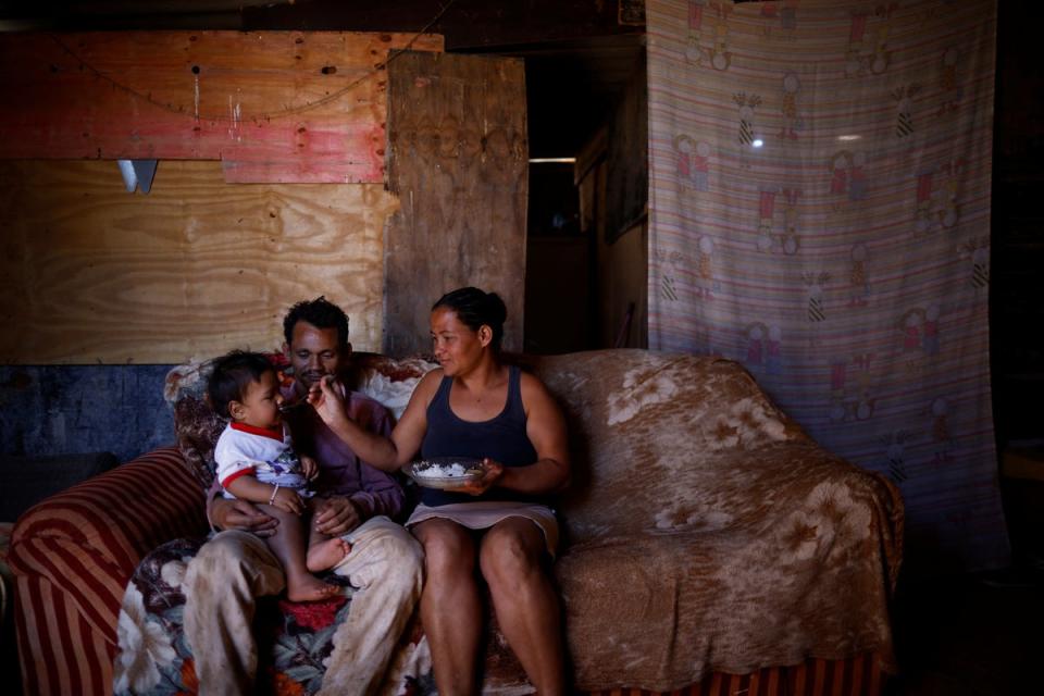 Luciana feeds her 10-month-old baby as he sits on the lap of her husband Felipe dos Santos, 26, at their home (Reuters)