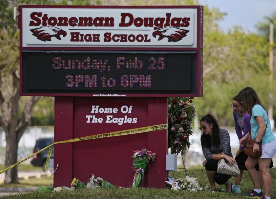 Los dolientes llevan flores mientras rinden homenaje en un monumento a las víctimas del tiroteo en la Secundaria Marjory Stoneman Douglas, el domingo 25 de febrero de 2018. Los padres y los estudiantes regresaron a la escuela por primera vez desde que 17 personas murieron en un tiroteo masivo en la escuela de Parkland el 14 de febrero.