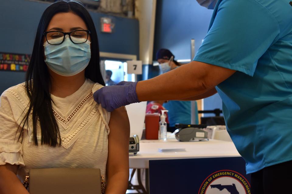 Lisa Luna, left, keeps her eyes shut as registered nurse Lily Mederos finishes administering the first dose of the Pfizer COVID-19 vaccine Monday, April 5, 2021, at the Fort Pierce Recreation Center. "I didn't think I was going to get [the vaccine]," said Luna, 25, of Fort Pierce, who attended the walk-in clinic with her parents. "People make it seem like it's such a scary thing to do." Identifying information on bar code sticker has been blurred.