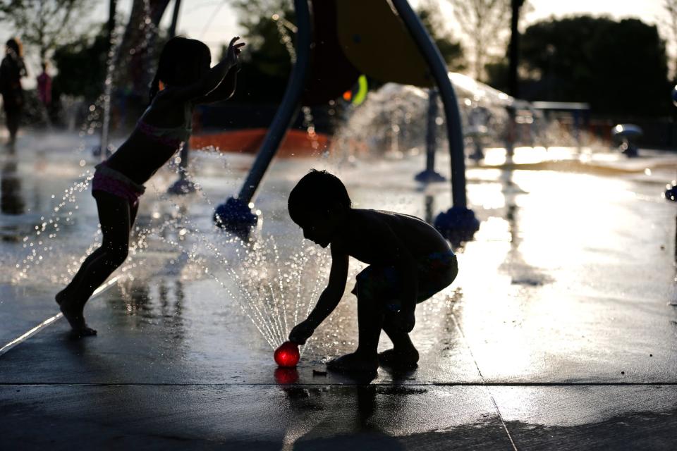 Nicole Casada jumps as her brother, Robbie Casada, plays with a fountain of water Aug. 6, 2015, in the Barnett Splash Pad in Edmond,.