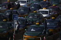 A taxi driver wearing a face mask stands watch as they pile up to wait for customers at a train station in Beijing, Thursday, Oct. 6, 2022. Sprawling Xinjiang is the latest Chinese region to be hit with sweeping COVID-19 travel restrictions, as China further ratchets up control measures ahead of a key Communist Party congress later this month. (AP Photo/Andy Wong)