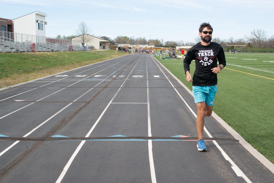Michael Kennett lightly jogs around the Seaman middle school track while athletes begin warming up in the background Monday afternoon. Kennett recently qualified for the Boston Marathon this year.