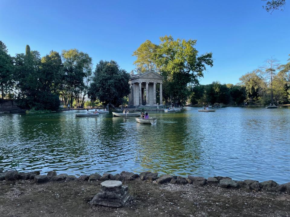 View of the gardens of Villa Borghese with a structure surrounded by water and trees