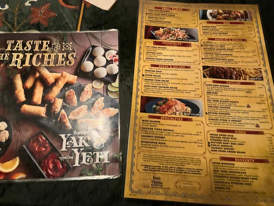 two menus from yak and yeti next to each other on a table at the animal kingdom restaurant